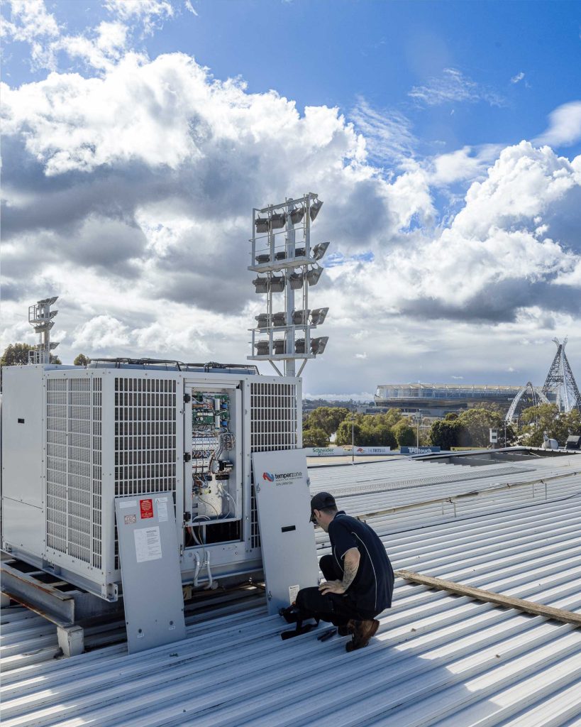 Man on a rooftop repairing a commercial air conditioning unit