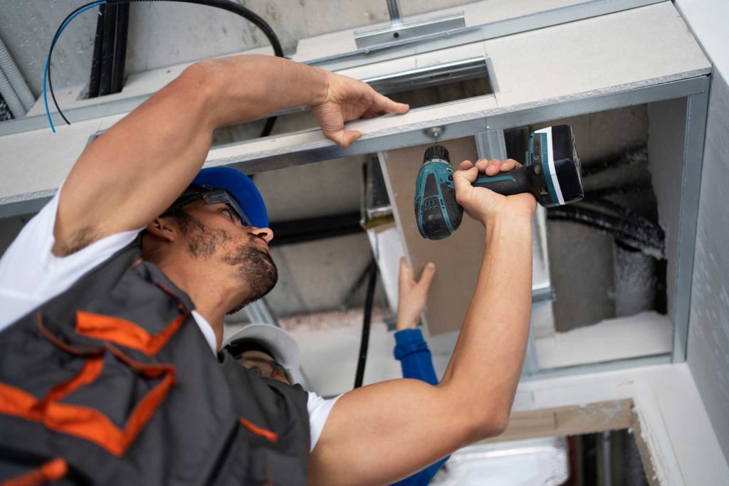 A worker repairing a commercial air conditioning unit