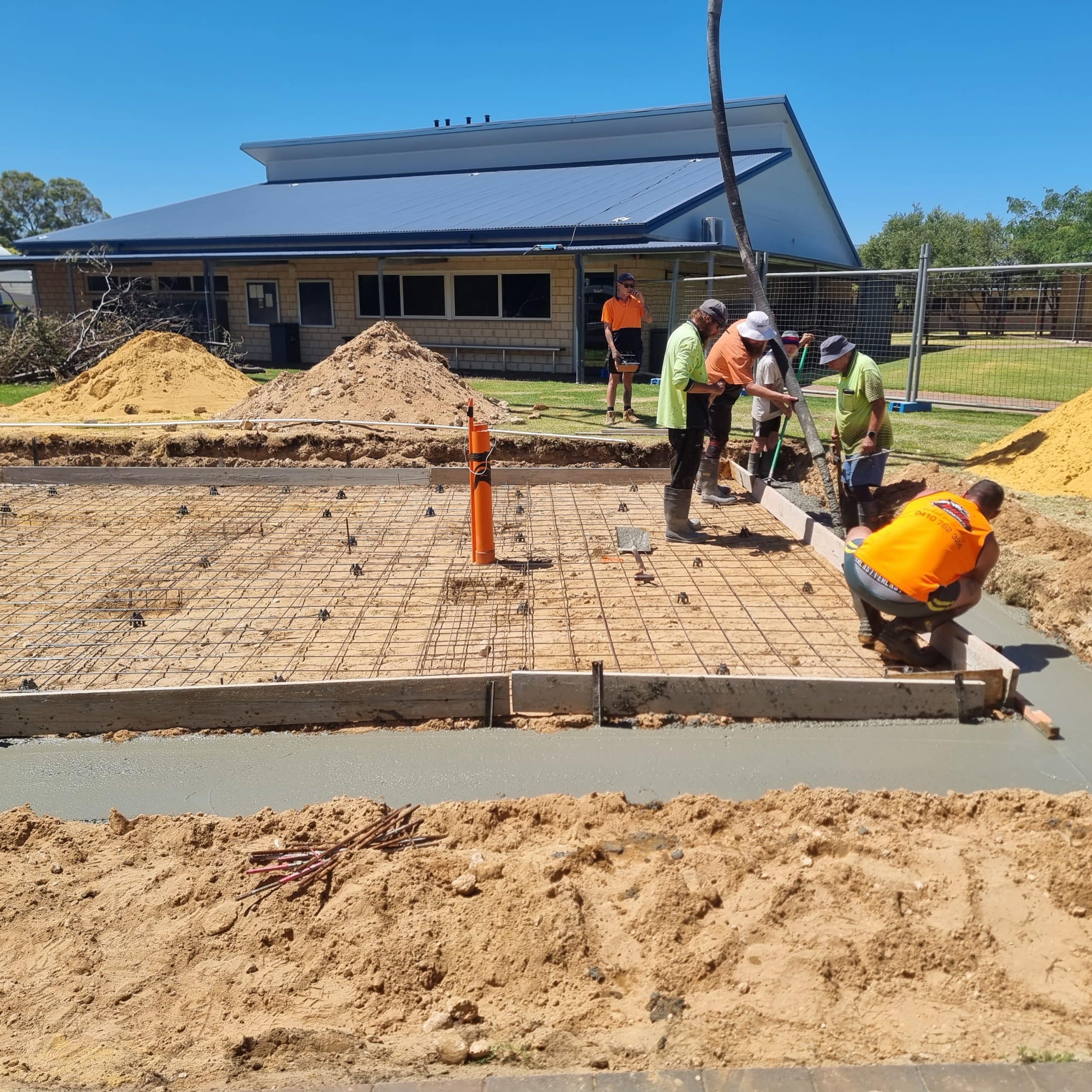 Labourers wearing hi vis and setting up the foundation for new concrete to be poured