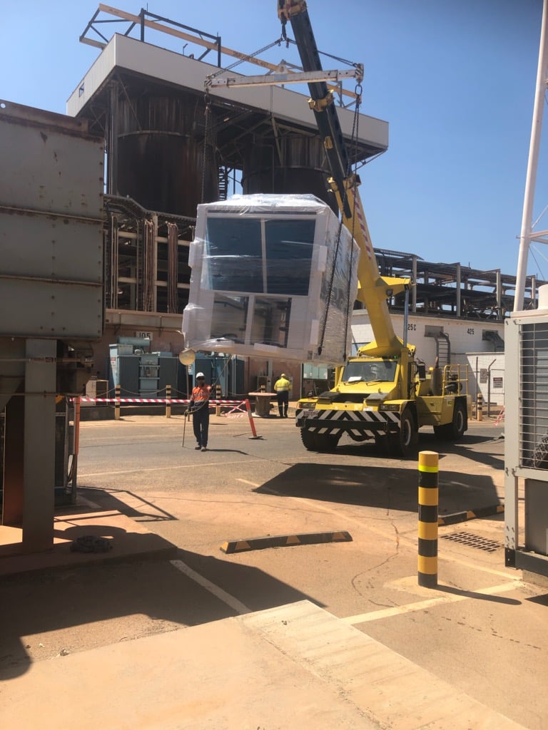 worker is directing the crane to transport the equipment