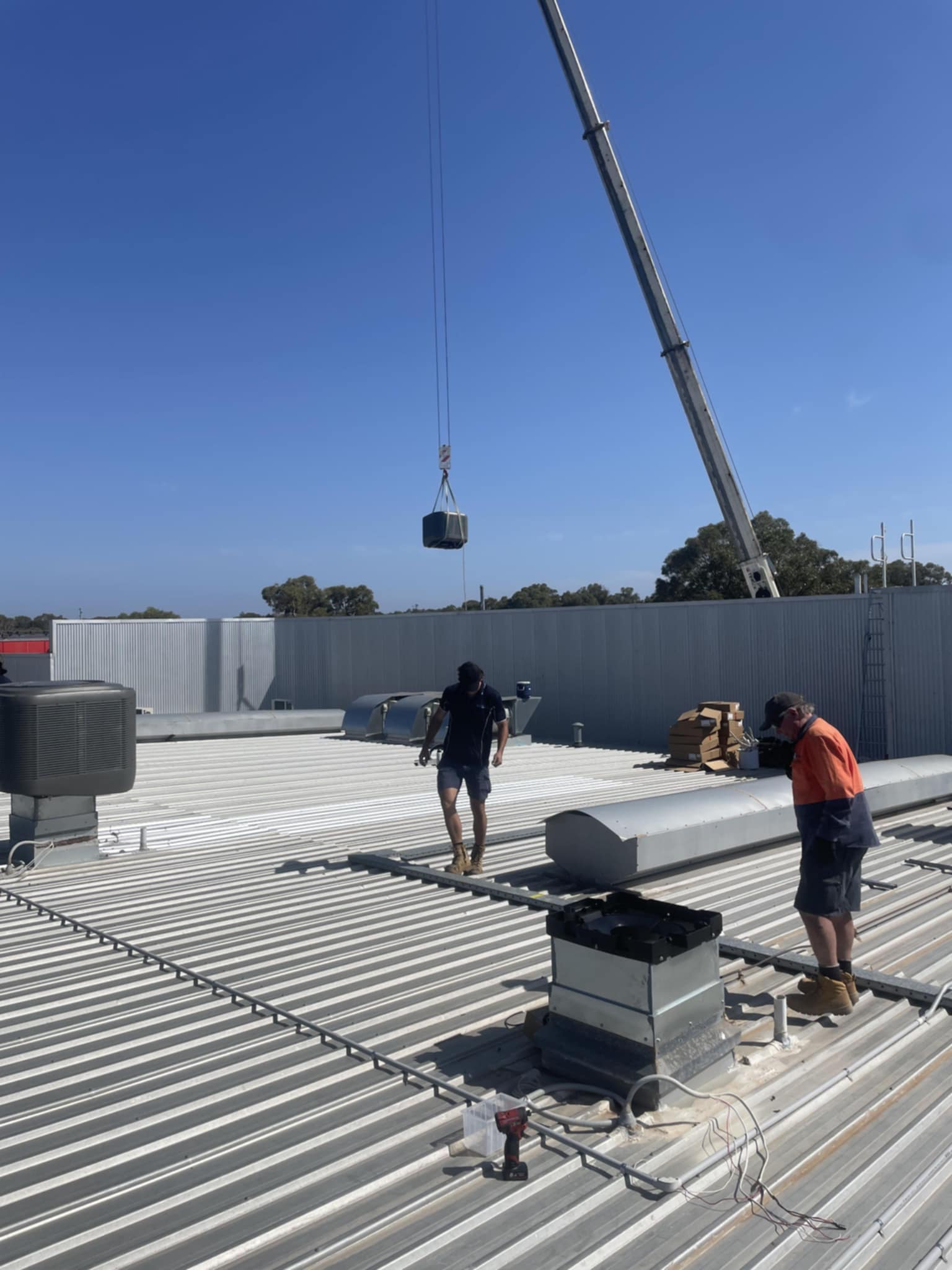 A crane suspends quipment to the roof