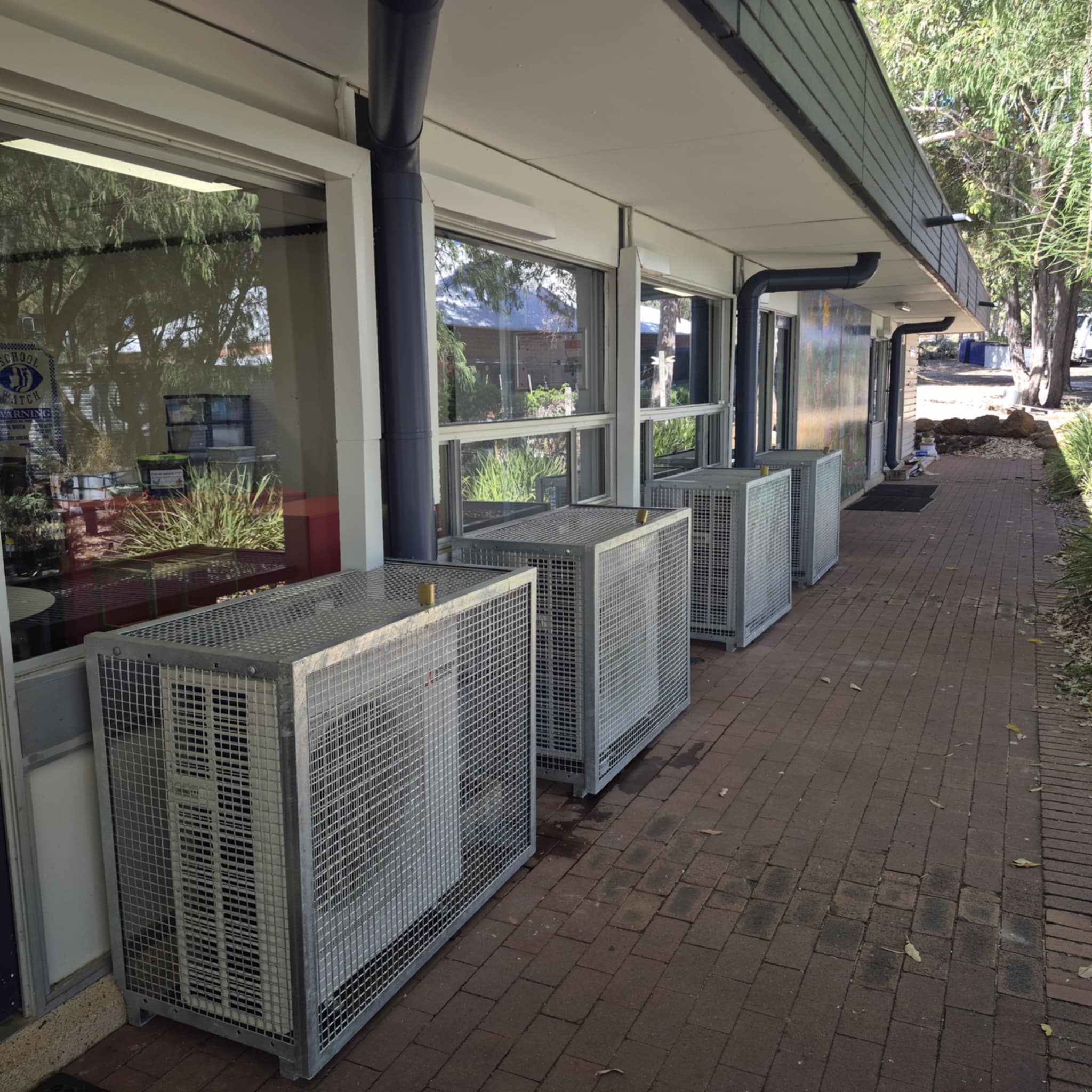 air conditioner outdoor unit mounted on the wall and covered with a metal frame