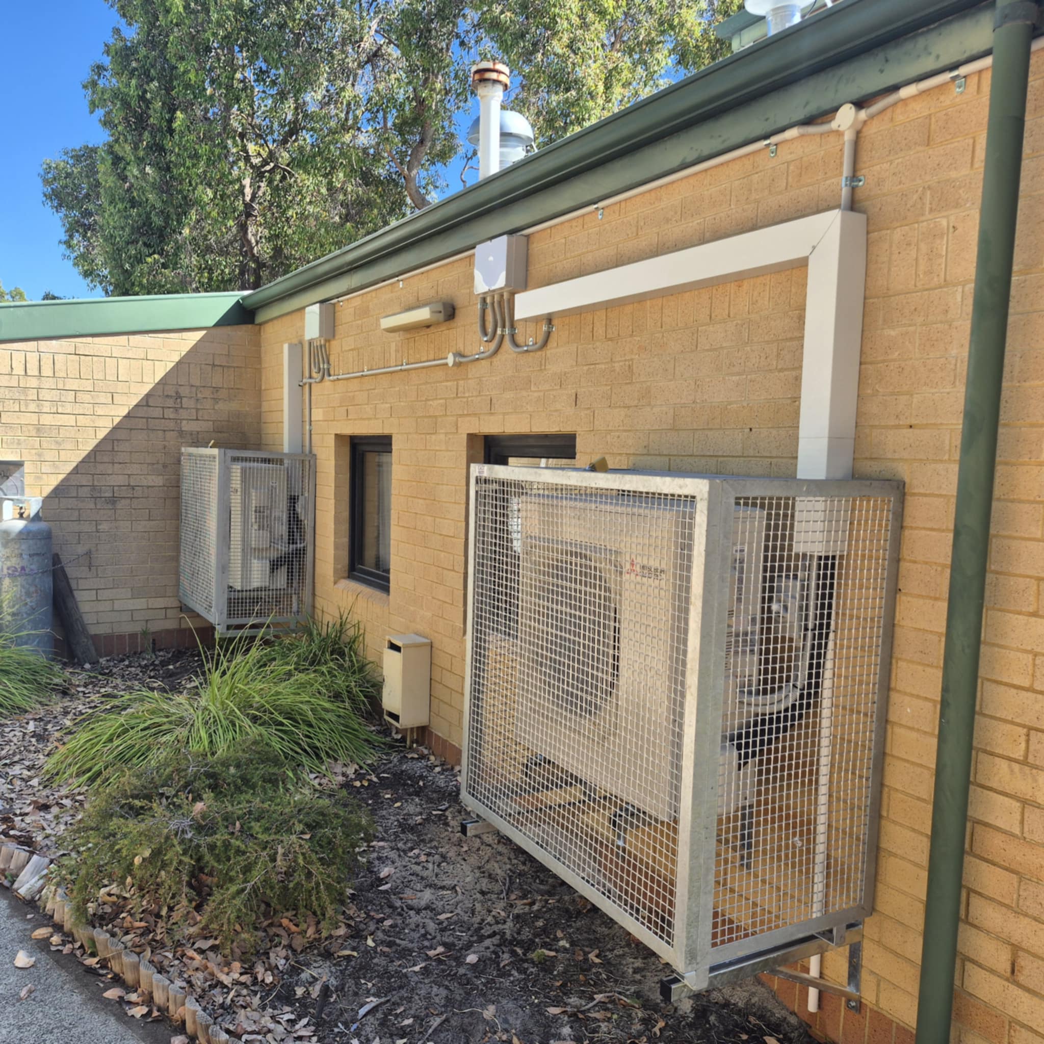air conditioner outdoor unit mounted on the wall and covered with a metal frame