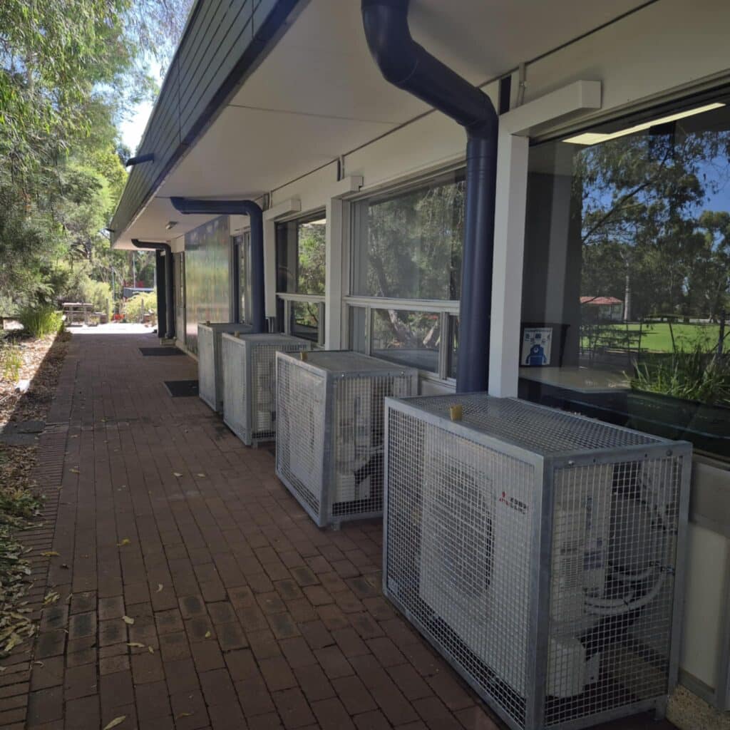 air conditioner outdoor unit mounted on the wall and covered with a metal frame