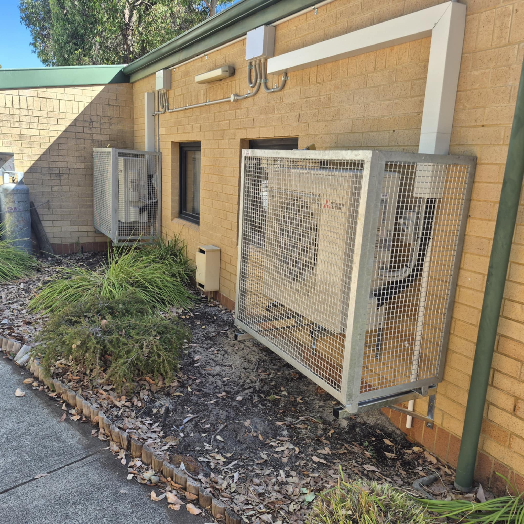 air conditioner outdoor unit mounted on the wall and covered with a metal frame