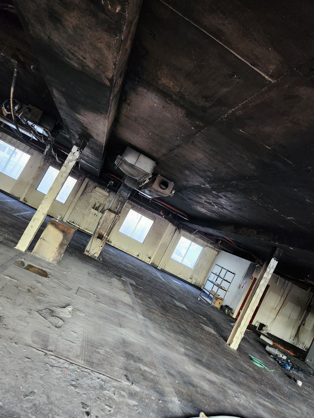 Fire-damaged commercial ceiling with smoke-stained HVAC ductwork awaiting replacement.
