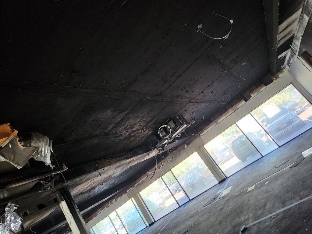 Interior showing extensive fire damage to ceiling and ventilation system before restoration.