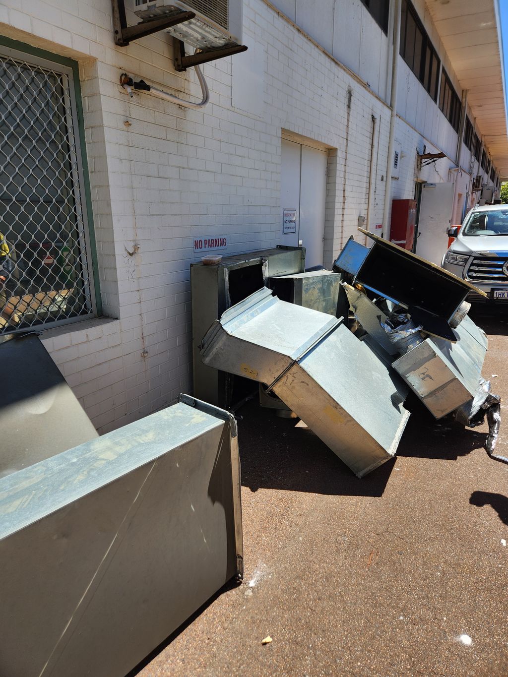 Removed HVAC ductwork stacked outside a commercial building during replacement works.